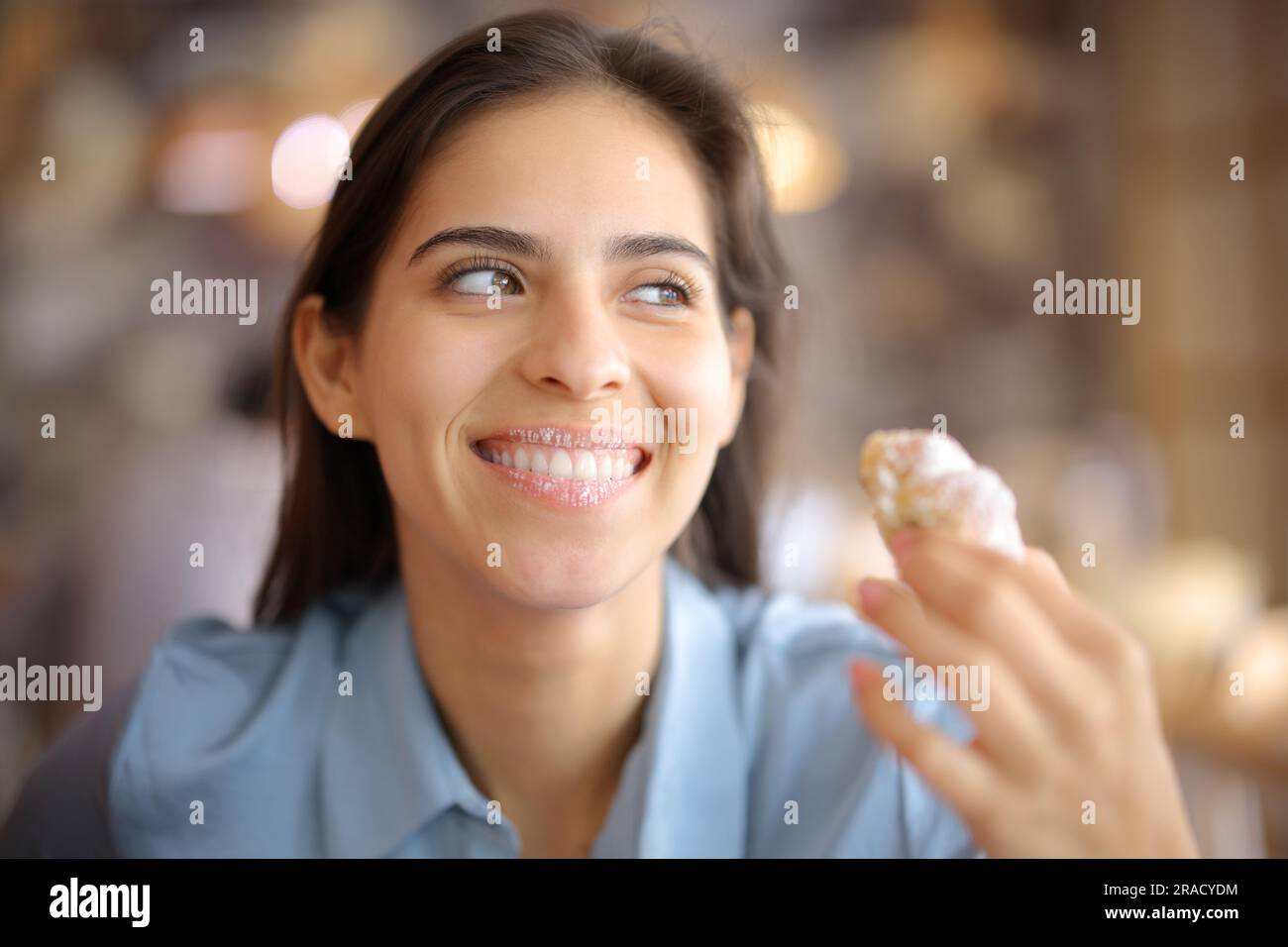 Le client du restaurant est content de manger un croissant avec des lèvres sales qui regardent loin Banque D'Images