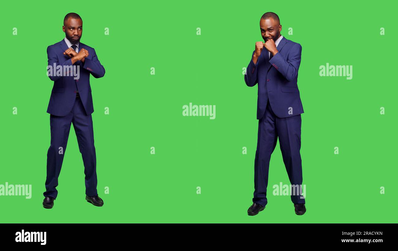 Le Manager afro-américain se prépare à faire des colis avec des poings, à frapper l'air et à agir de manière agressive sur fond vert. Les entrepreneurs en colère se battent et se font violemment en studio. Banque D'Images