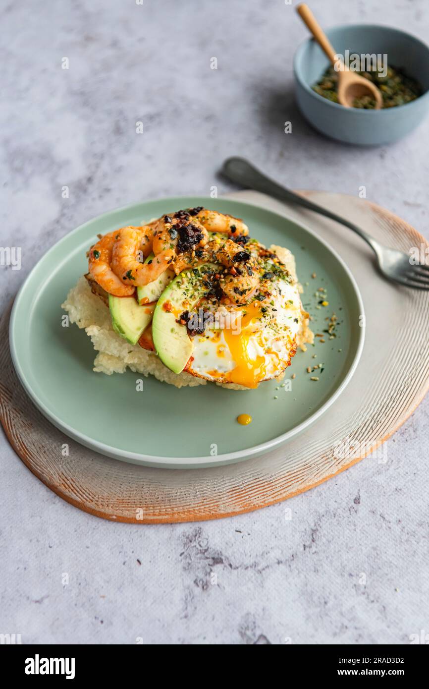 Riz sushi frit avec œuf frit, crevettes, avocat, piment croustillant et furikake nori Banque D'Images