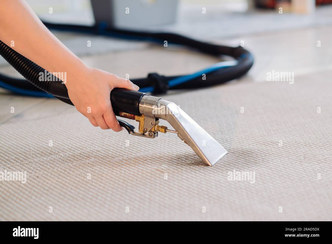 Gros plan de la femme de ménage tenant un aspirateur de lavage moderne et nettoyant la moquette sale avec une tache avec un détergent professionnel. Banque D'Images