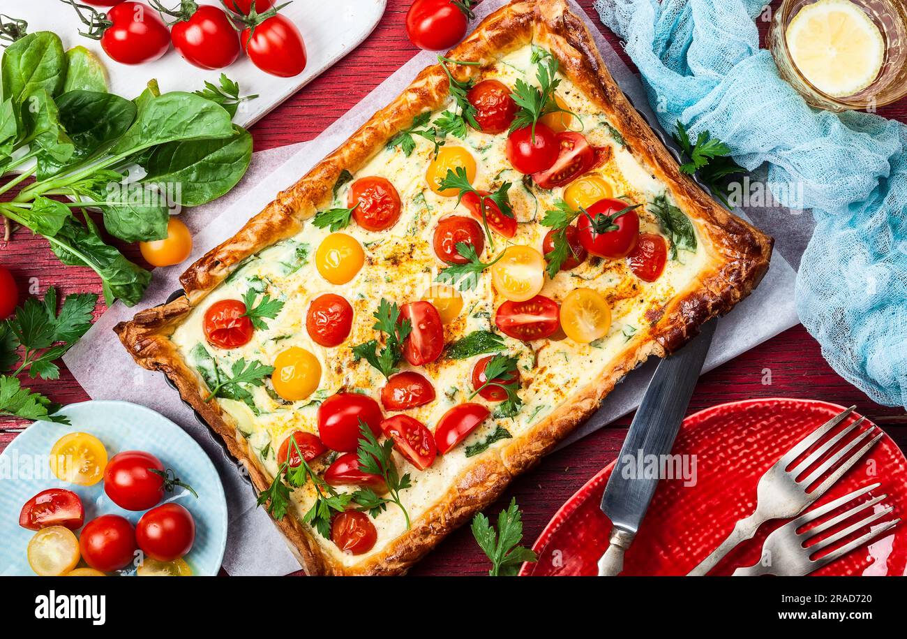 Tarte aux tomates délicieusement simple faite avec une pâte feuilletée, des tomates cerises rouges et jaunes, des épinards et de la ricotta. L'apéritif parfait pour l'été. Co Banque D'Images