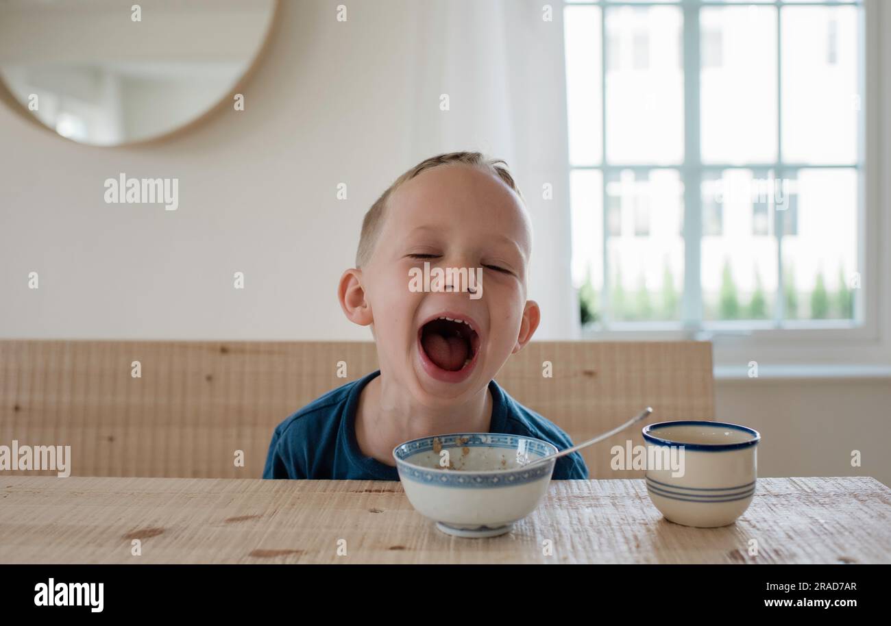 portrait d'un jeune garçon blond qui rit à l'heure du petit-déjeuner Banque D'Images