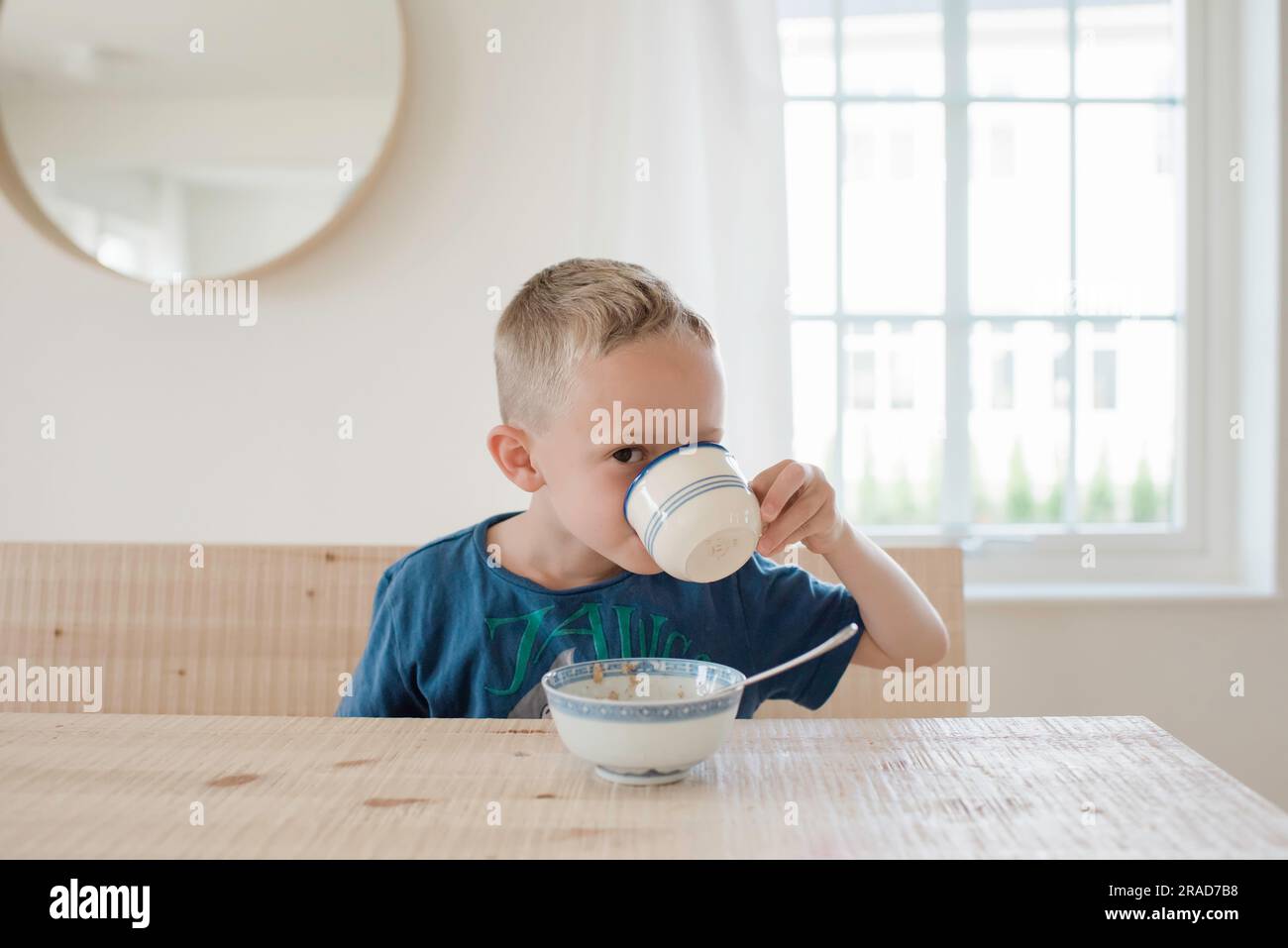 portrait d'un jeune garçon regardant avec un seul oeil boire au petit déjeuner Banque D'Images