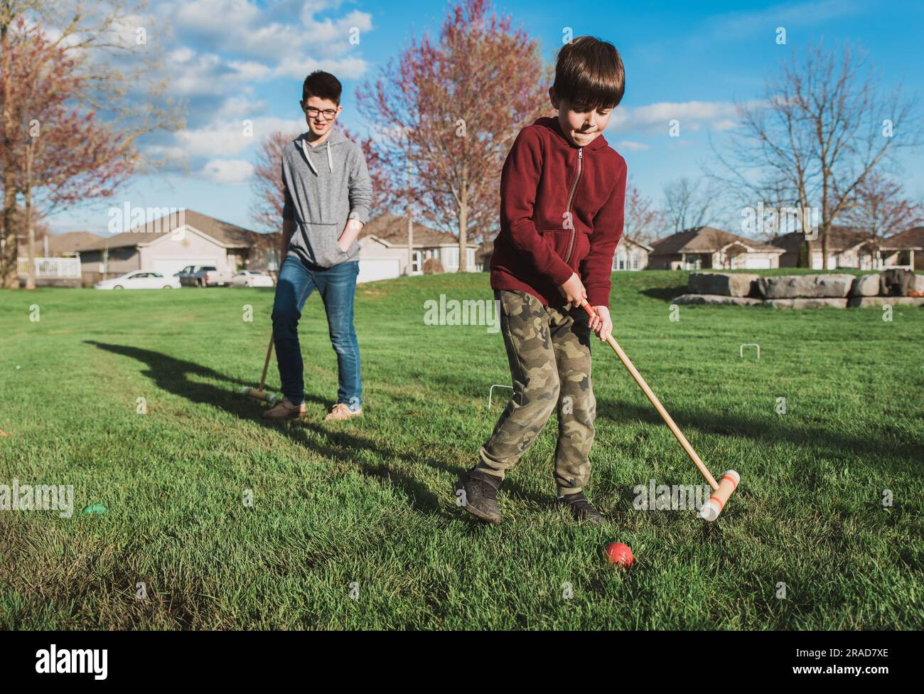 Deux garçons jouant ensemble un jeu de croquet dans un parc. Banque D'Images
