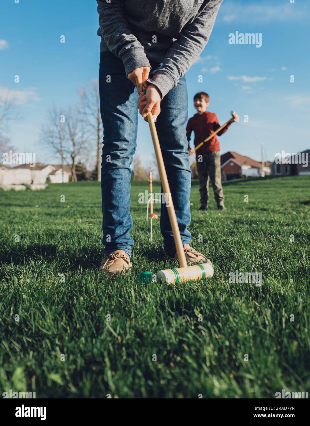 Deux garçons jouant au croquet dans un parc par temps ensoleillé. Banque D'Images