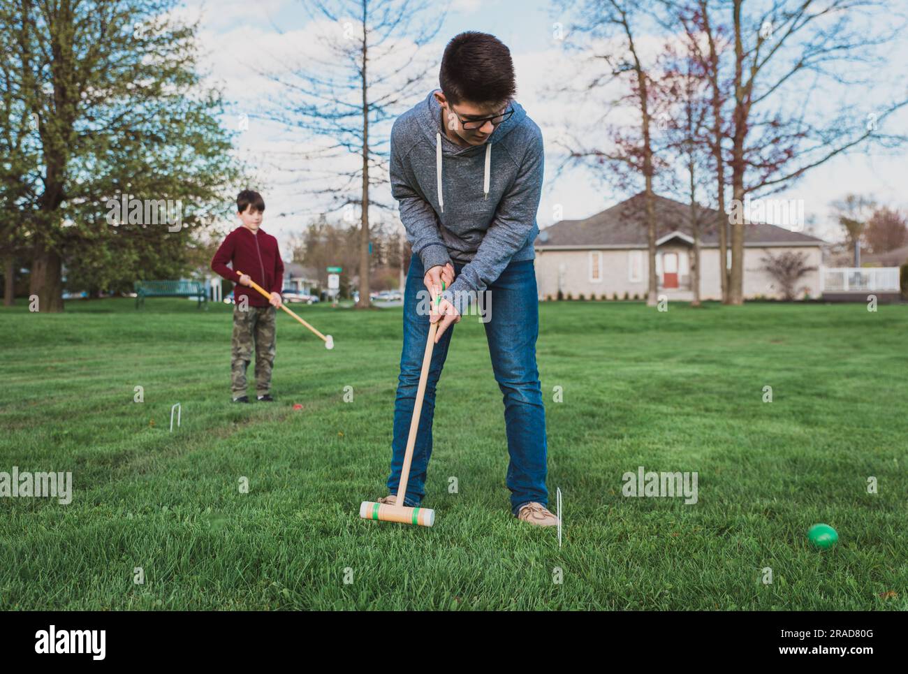 Deux garçons jouant ensemble un jeu de croquet dans un parc. Banque D'Images