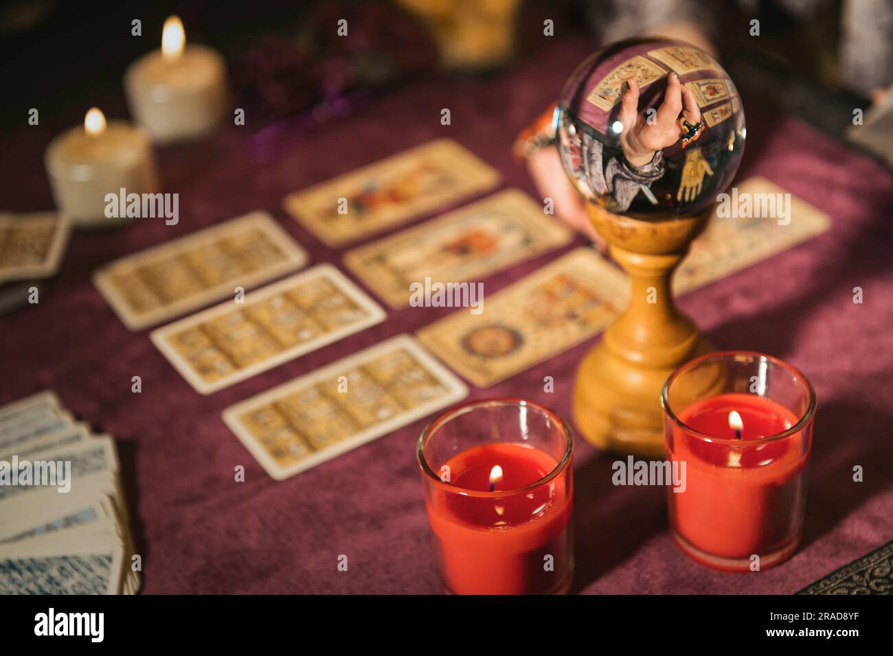 Mise au point sélective de boule de cristal reflétant la récolte apaisante prédire l'avenir avec des cartes de tarot près de bougies allumées sur la table contre un arrière-plan flou Banque D'Images