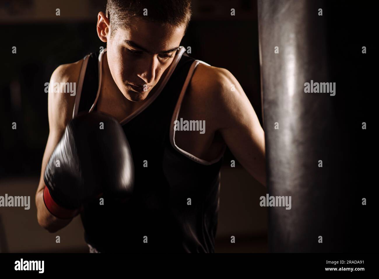 Gros plan d'un jeune boxeur pratiquant une boxe à succès pendant l'entraînement. Banque D'Images
