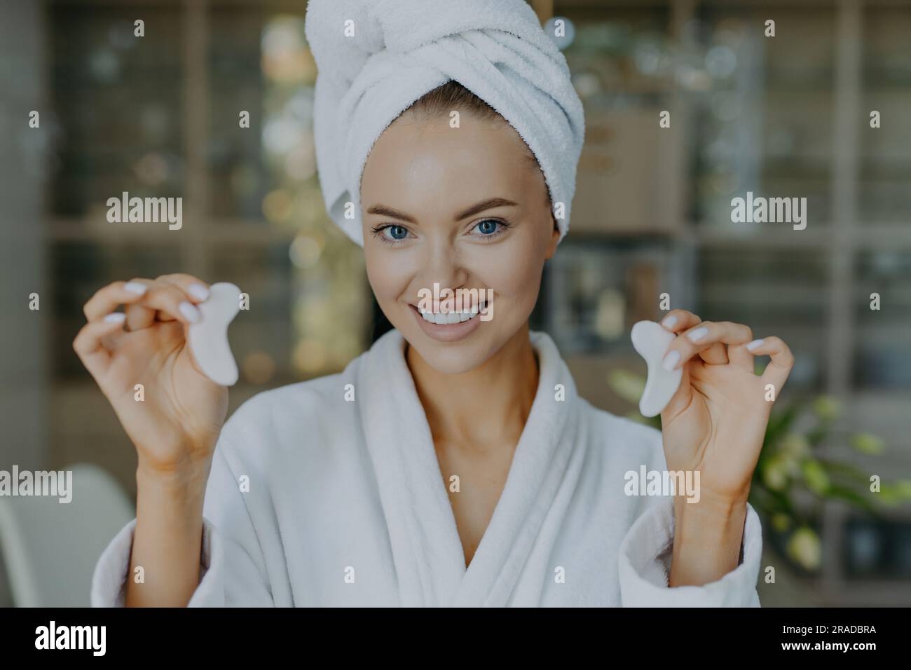 Une femme européenne souriante avec une peau fraîche tient des taches, élimine les cercles sombres, porte un peignoir, un regard positif. Banque D'Images