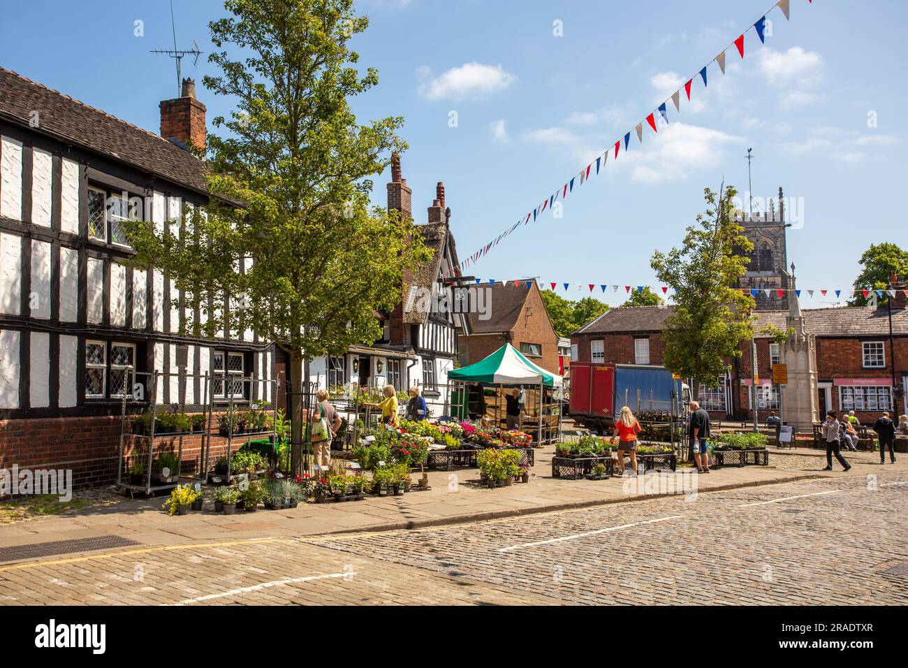 Les gens font du shopping dans un étal d'usine au marché hebdomadaire dans la ville de Sandbach dans le Cheshire, en face de l'auberge de coaching d'ours noir du 17e siècle Banque D'Images