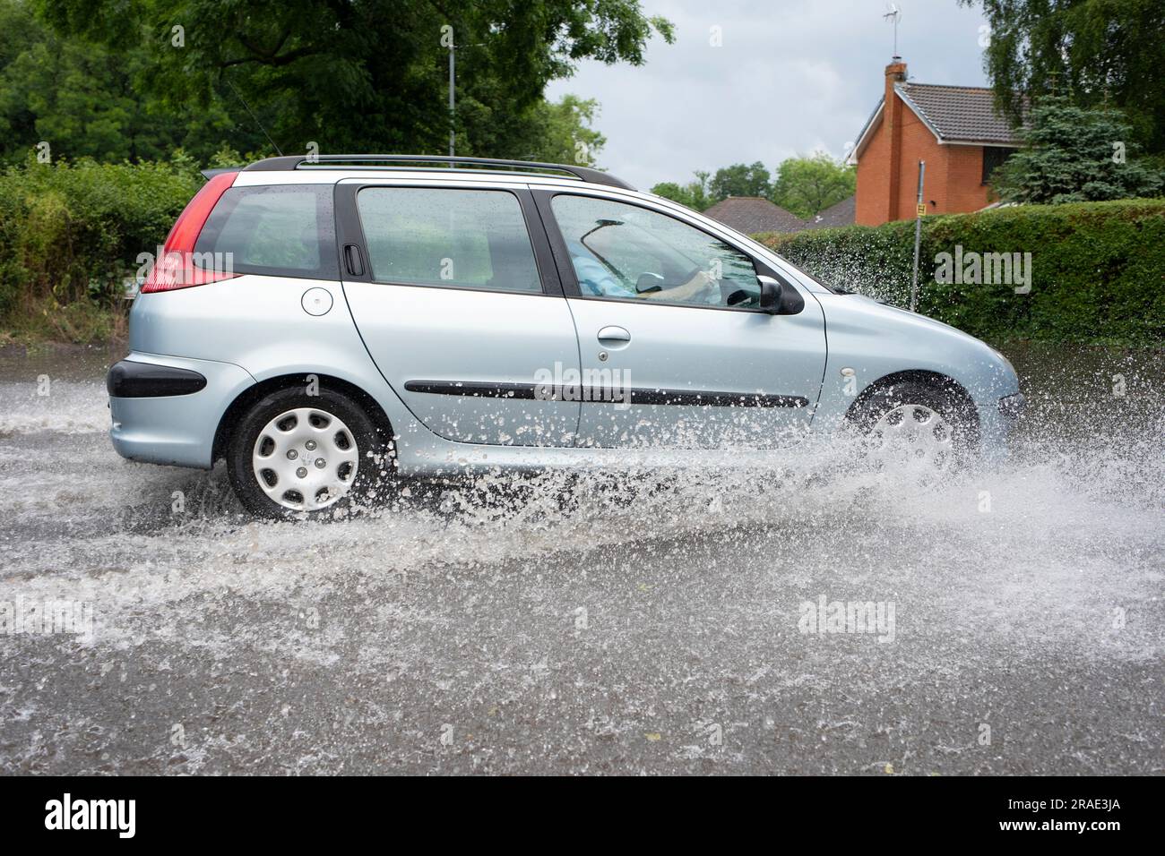 Un automobiliste qui traverse les eaux de crue après une tempête de pluie à Redditch, dans le Worcestershire. Banque D'Images