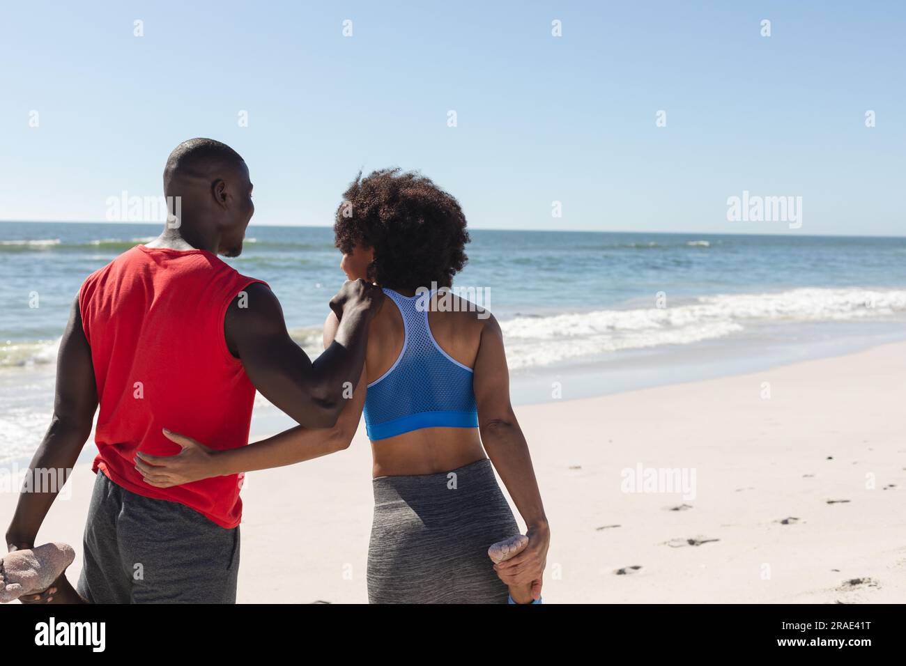 Heureux, en forme couple afro-américain s'exerçant, s'étirant et embrassant sur la plage ensoleillée, espace de copie Banque D'Images