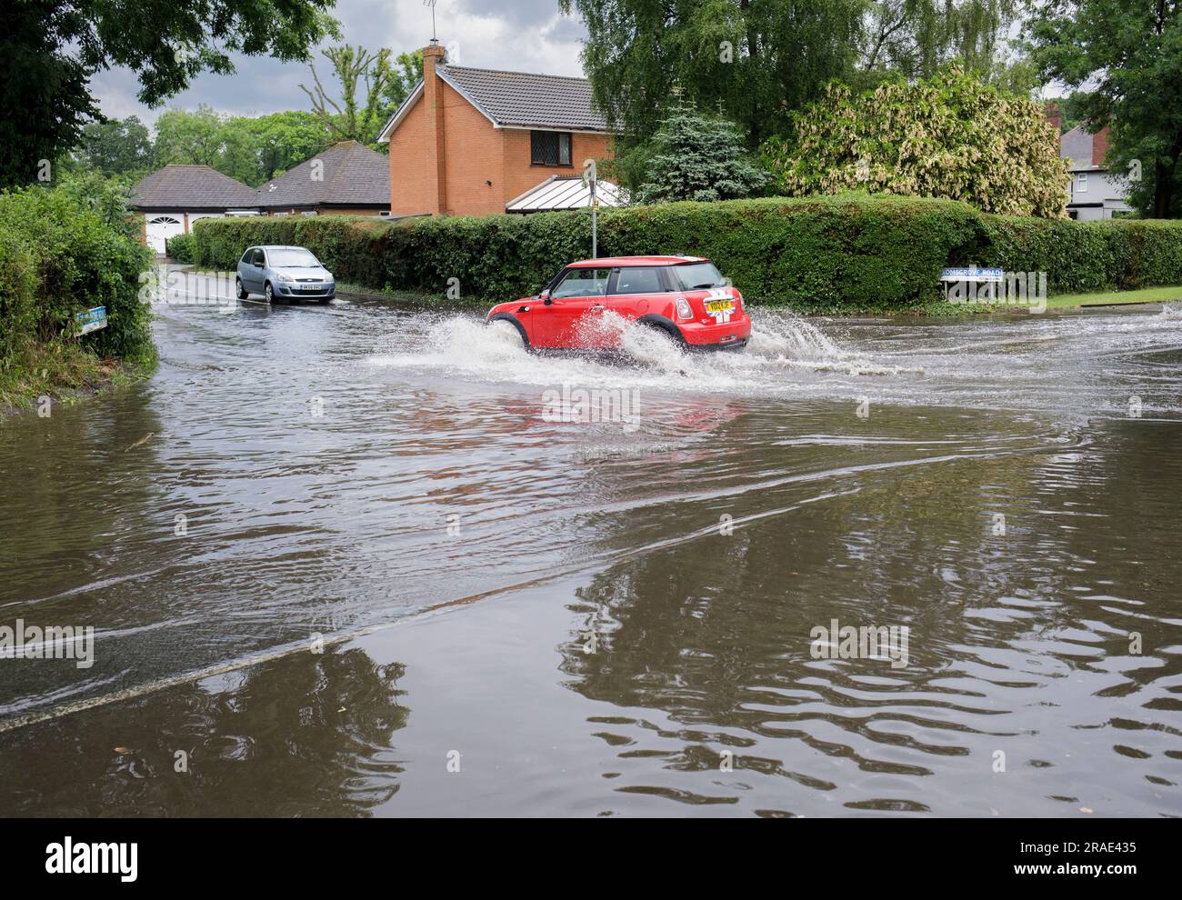 Les automobilistes qui traversent les eaux de crue après une tempête de pluie à Redditch, dans le Worcestershire. Banque D'Images