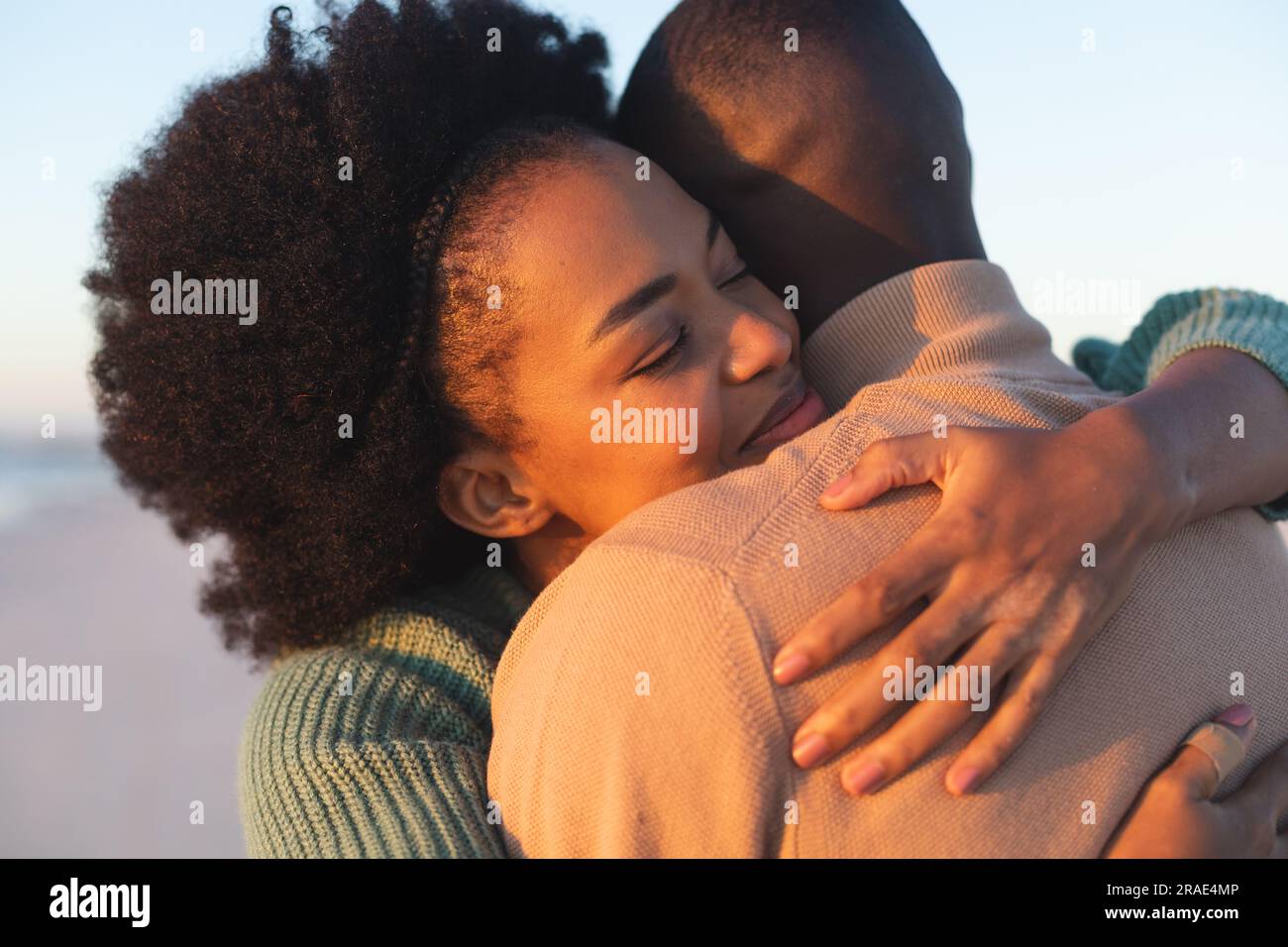 Heureux couple afro-américain embrassant et souriant sur la plage ensoleillée Banque D'Images