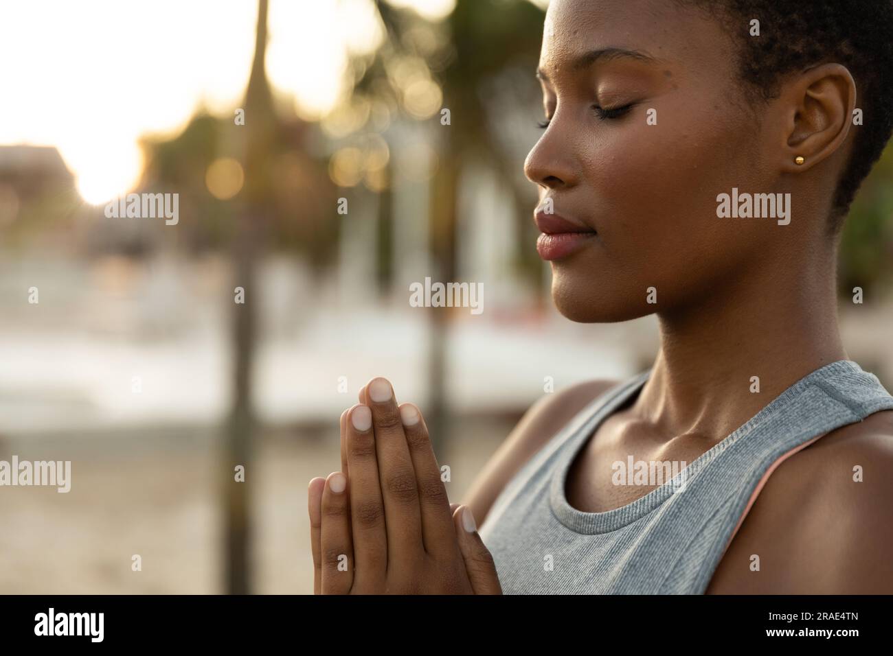 Femme afro-américaine détendue pratiquant la méditation de yoga sur la plage ensoleillée, espace de copie Banque D'Images