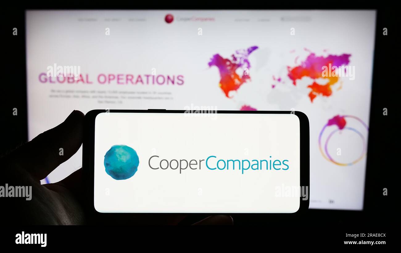 Personne tenant un smartphone avec le logo de la société américaine The Cooper Companies Inc. Sur l'écran devant le site Web. Concentrez-vous sur l'affichage du téléphone. Banque D'Images