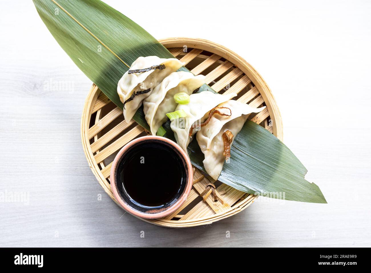 Dim Sum frit orientale avec de la viande hachée également connu sous le nom de Gyoza, Dim Sum, Jiaozi ou Momo sur une feuille de banane avec sauce épicée gros plan. Bœuf et RAM fine chaude Banque D'Images