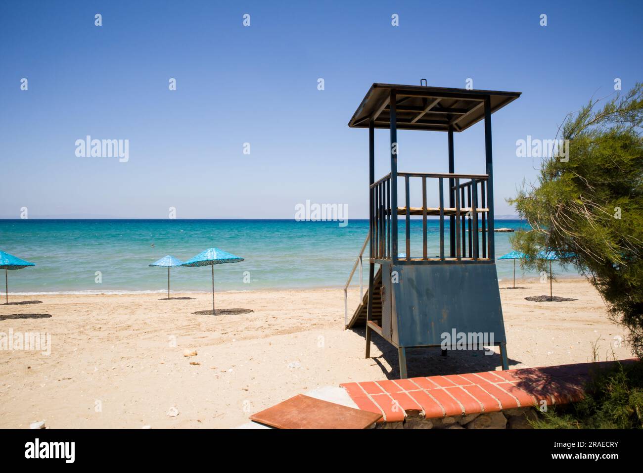 Tour de guet de sauveteur vide avec parasols en paille bleue sur la plage Banque D'Images