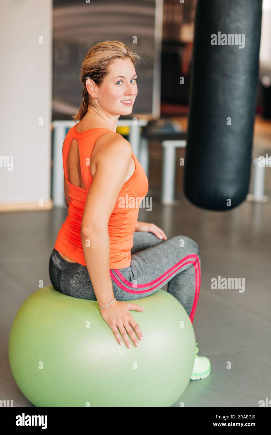 Jeune femme forte assise sur le ballon de fitness Banque D'Images