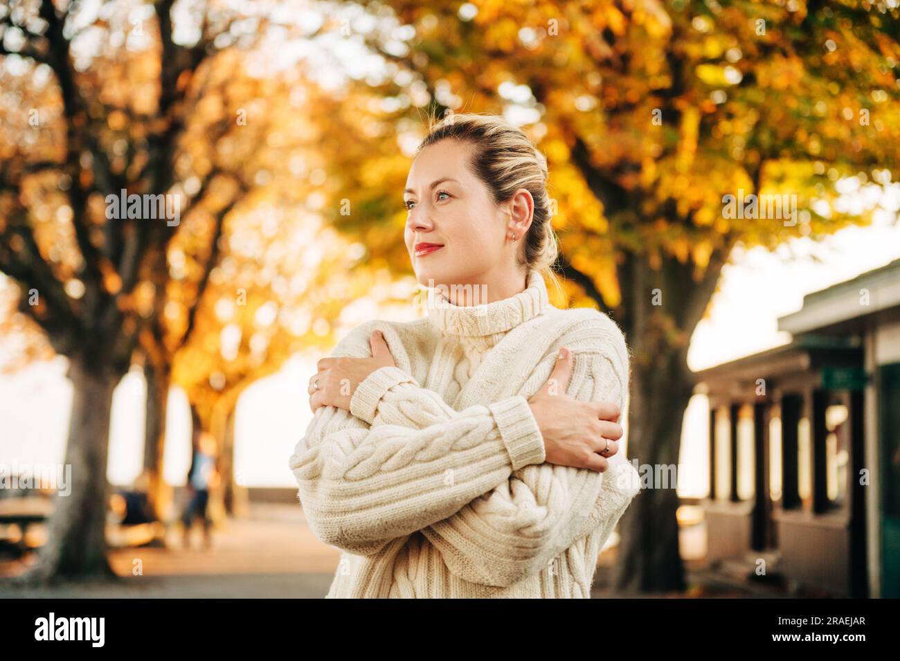 Portrait d'automne de la jeune femme heureuse portant un pull blanc tricoté Banque D'Images