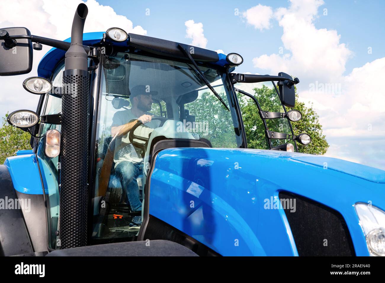 Agriculteur conduisant un tracteur agricole bleu. Banque D'Images