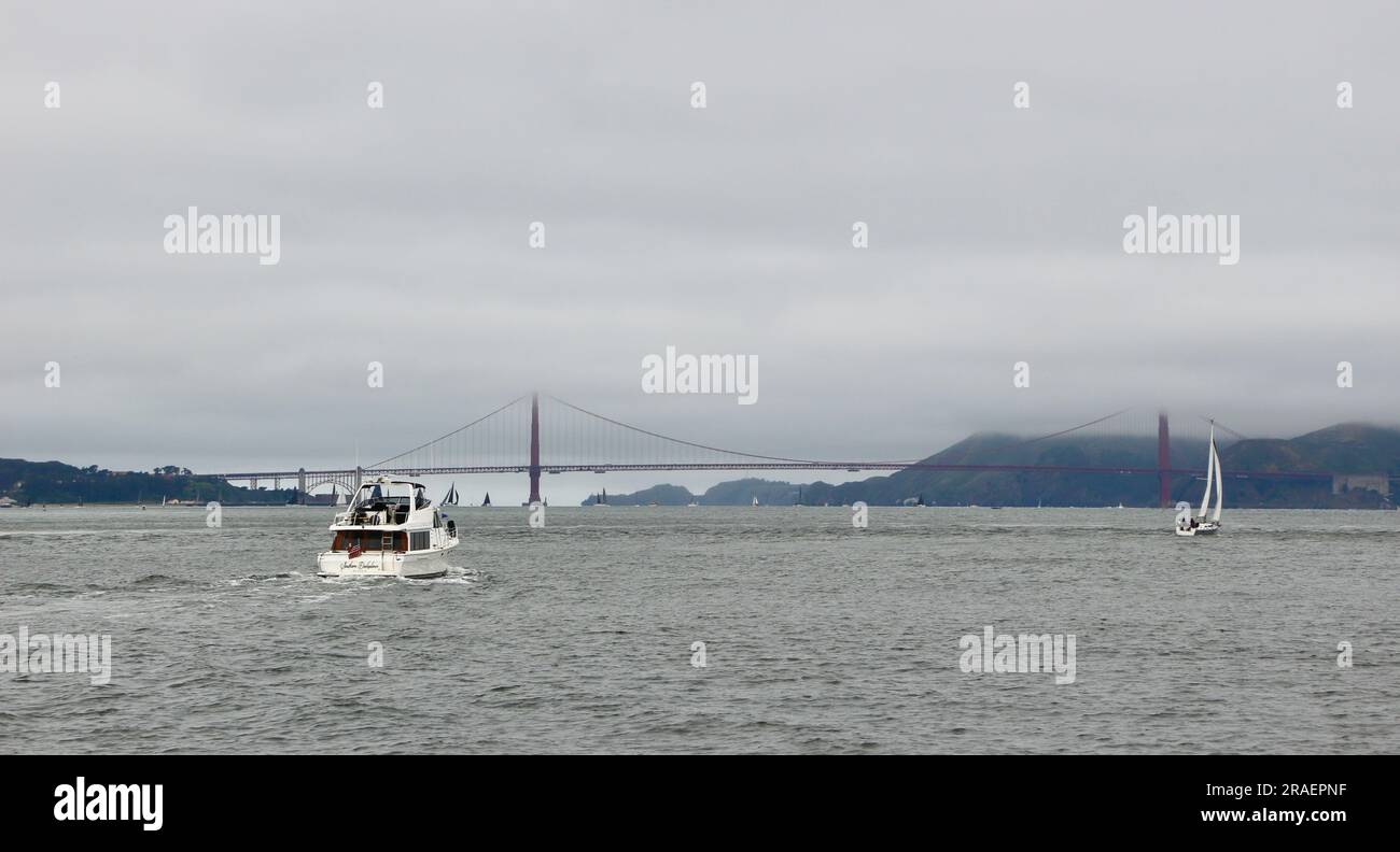Nuage bas au-dessus du pont du Golden Gate avec un bateau à moteur et des yachts lointains vus à bord d'un bateau touristique dans la baie de San Francisco Californie USA Banque D'Images
