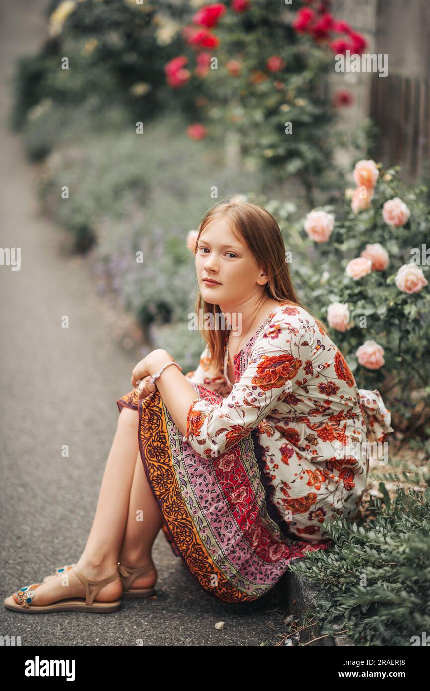 Portrait d'été de la jolie petite fille portant une robe colorée, posant dans un jardin de roses Banque D'Images