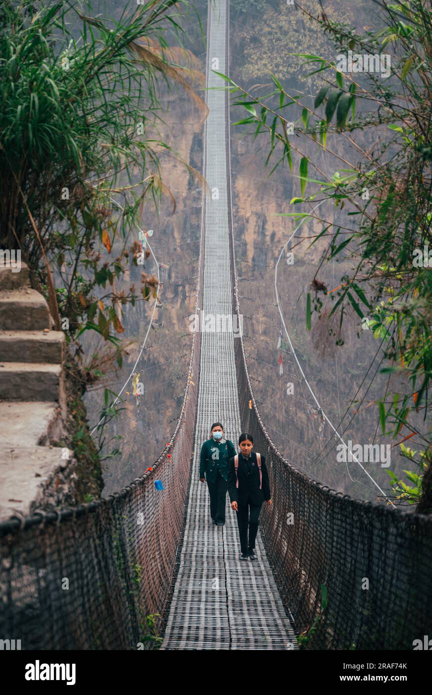 Pokhara, Népal - 15 avril 2023 : le peuple népalais franchit le pont suspendu de Bhalam au-dessus de la rivière Seti près de Pokhara. Banque D'Images