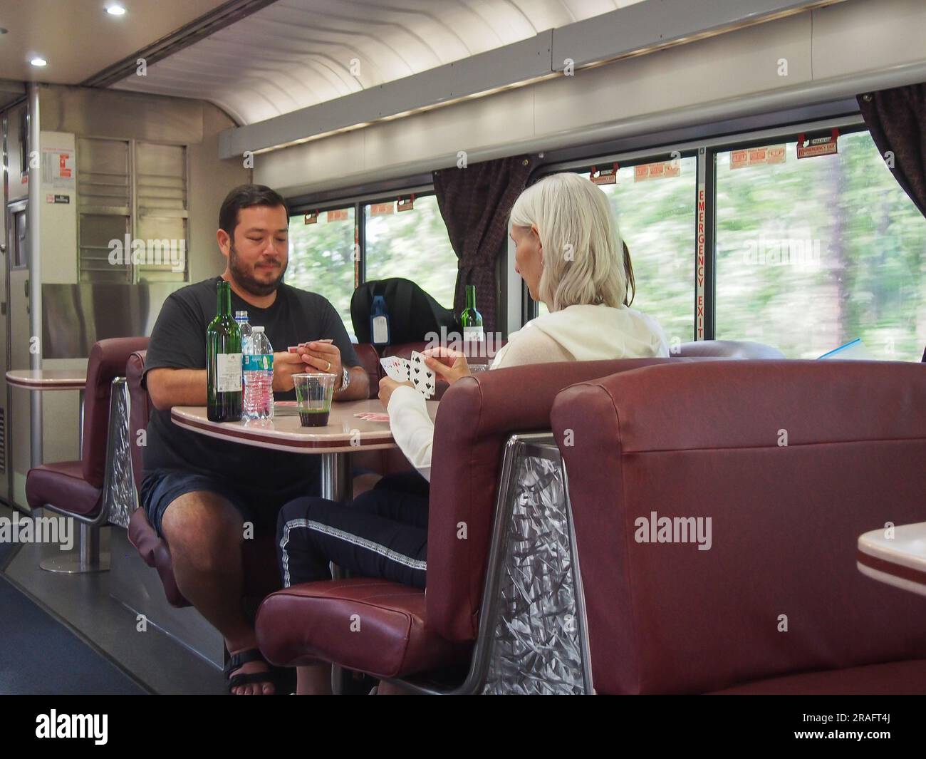 Les passagers jouant à un jeu de cartes et buvant du vin dans le wagon-bar à bord du train automatique Amtrak en route de Sanford, Floride, à Lorton, Virginie, juin Banque D'Images