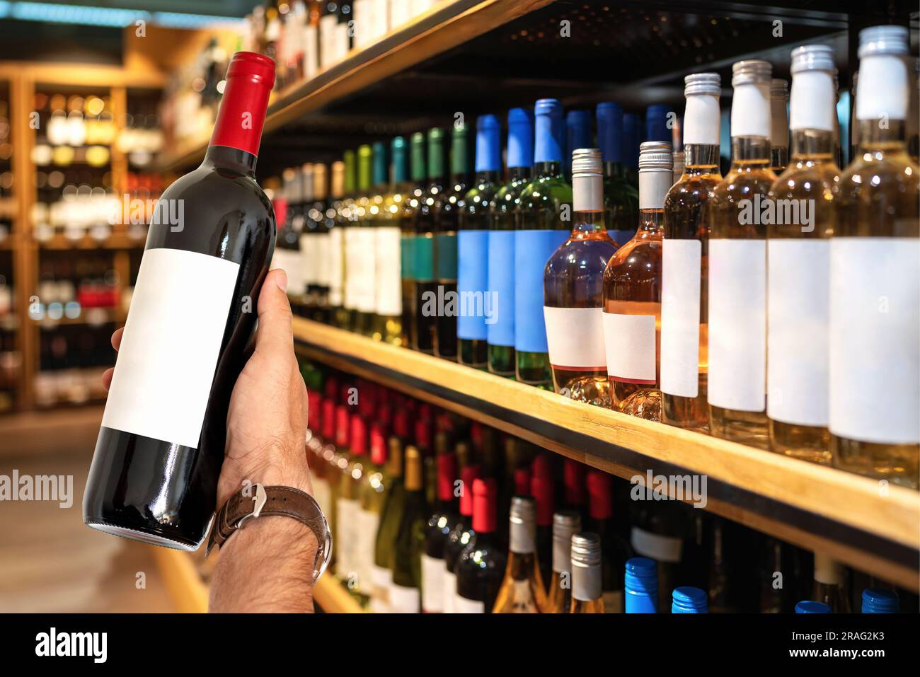 Bouteille de vin avec une étiquette vierge à la disposition du client sur le fond des étagères avec du vin en magasin. Banque D'Images
