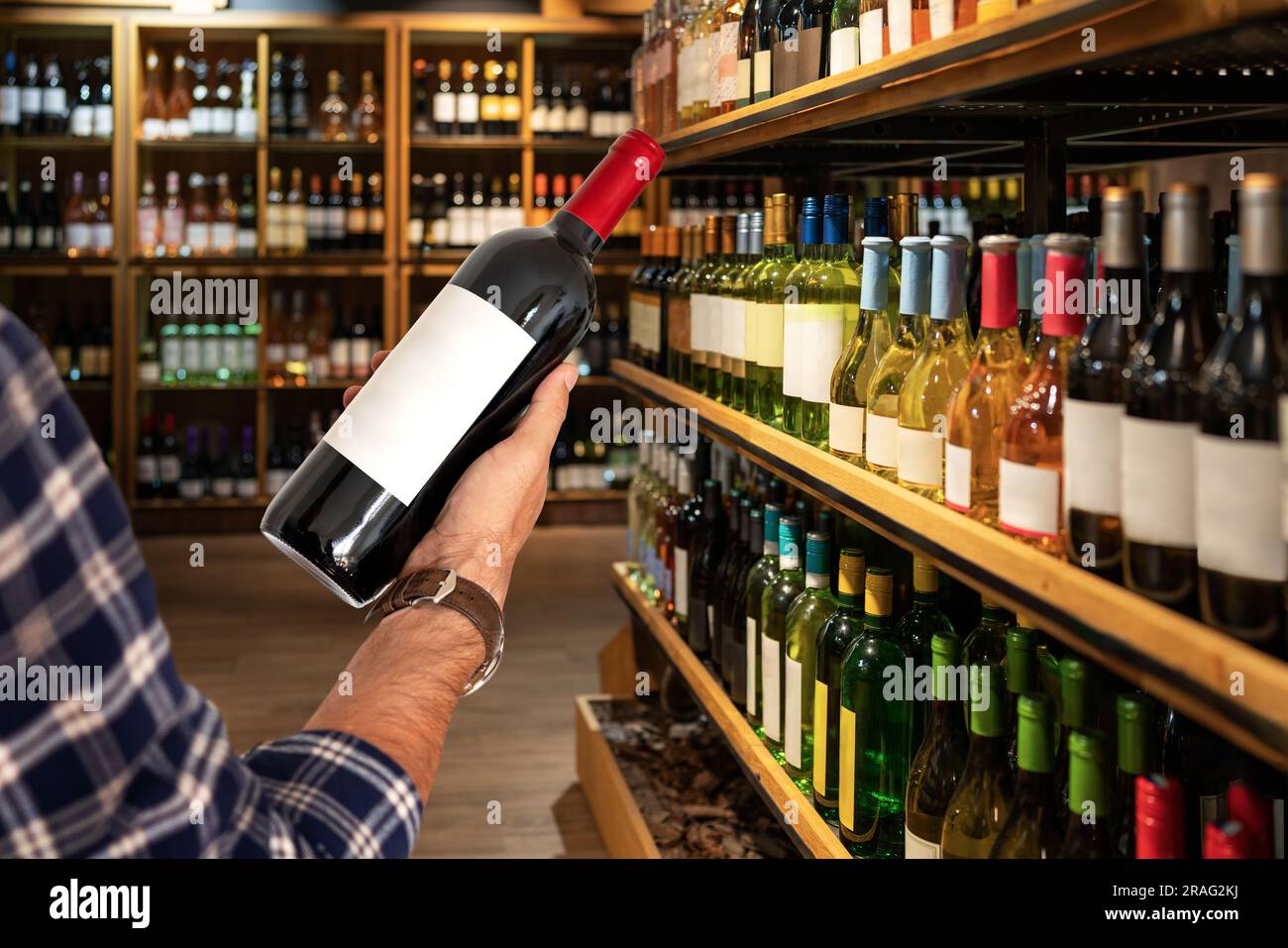 Bouteille de vin rouge à la main du client sur les étagères avec vin en magasin. Banque D'Images