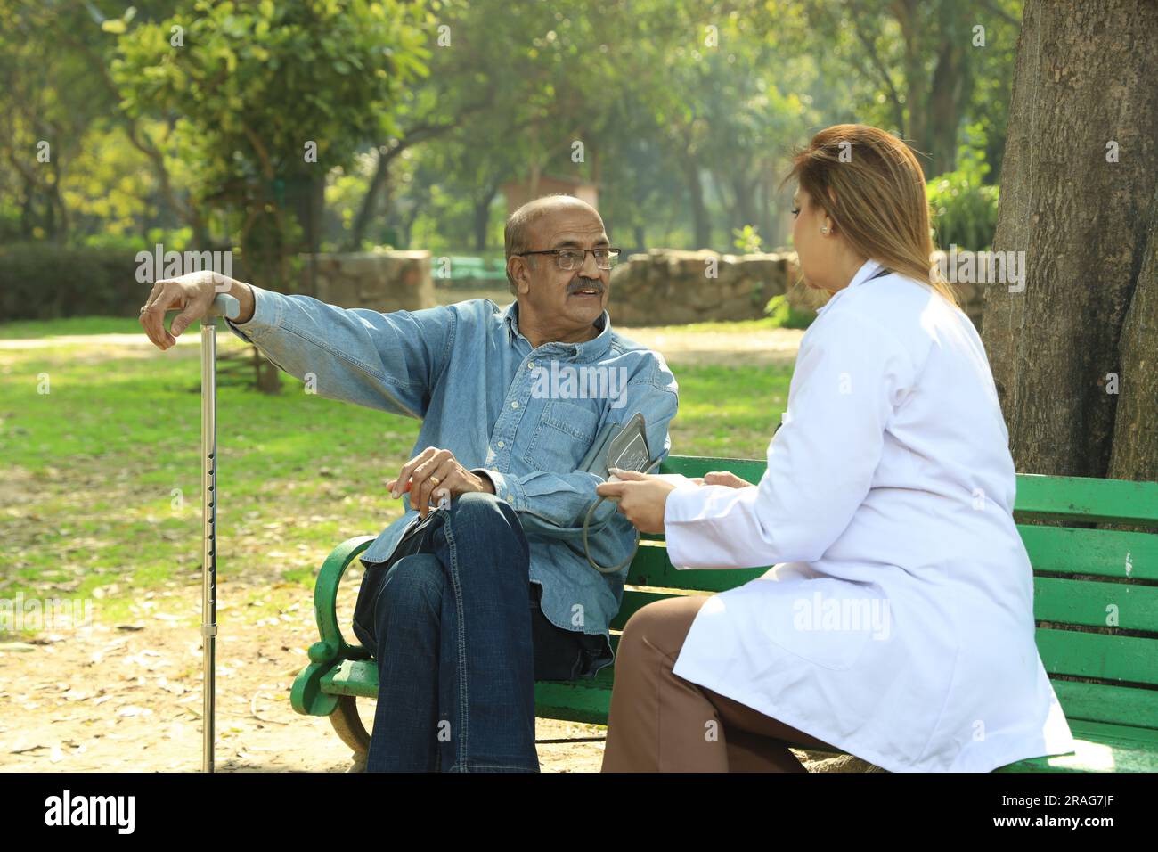 Femme médecin indienne examinant le patient âgé dans le parc de la ville dans l'après-midi. Banque D'Images