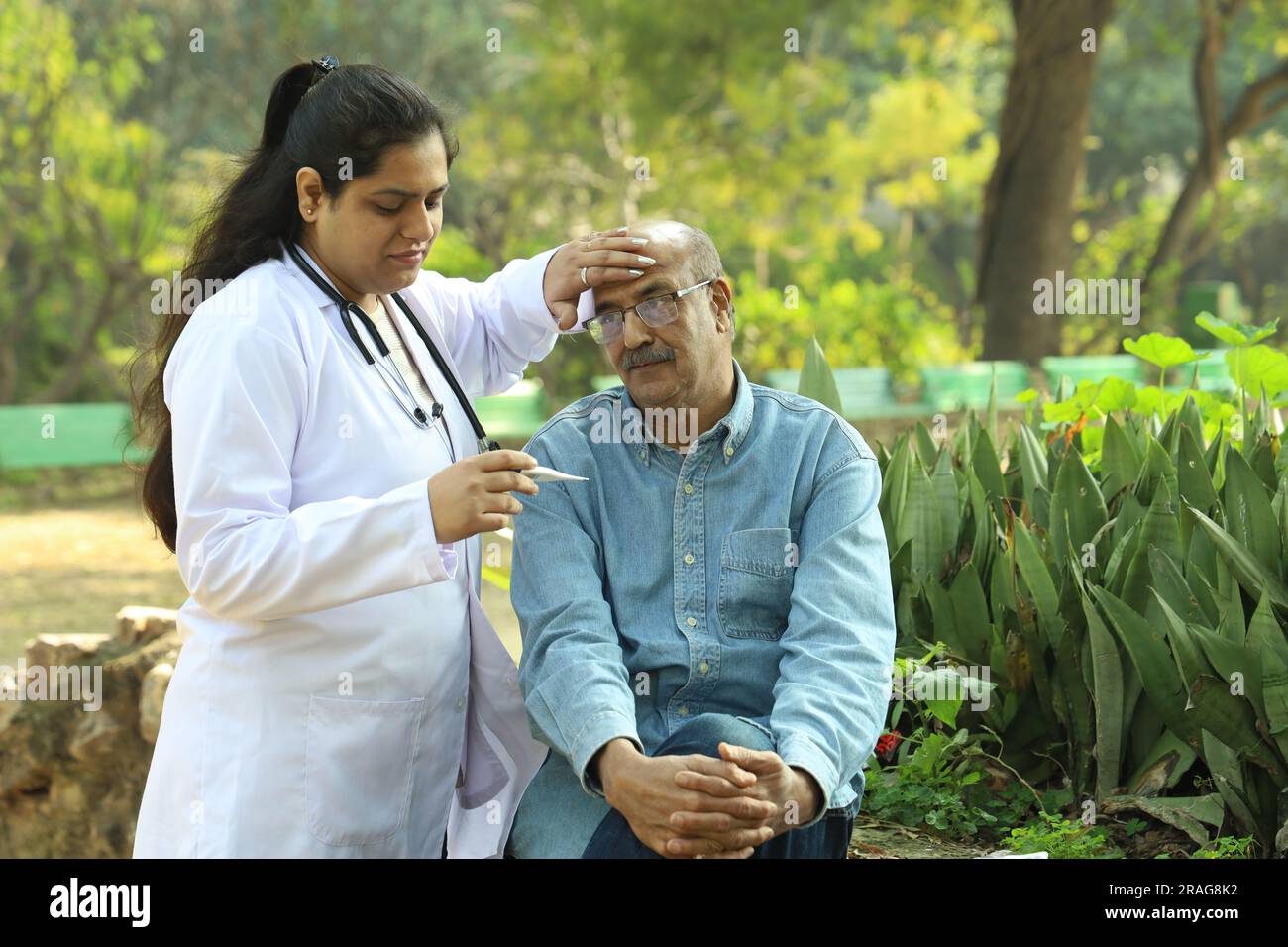 Femme médecin indienne examinant le patient âgé dans le parc de la ville dans l'après-midi. Banque D'Images