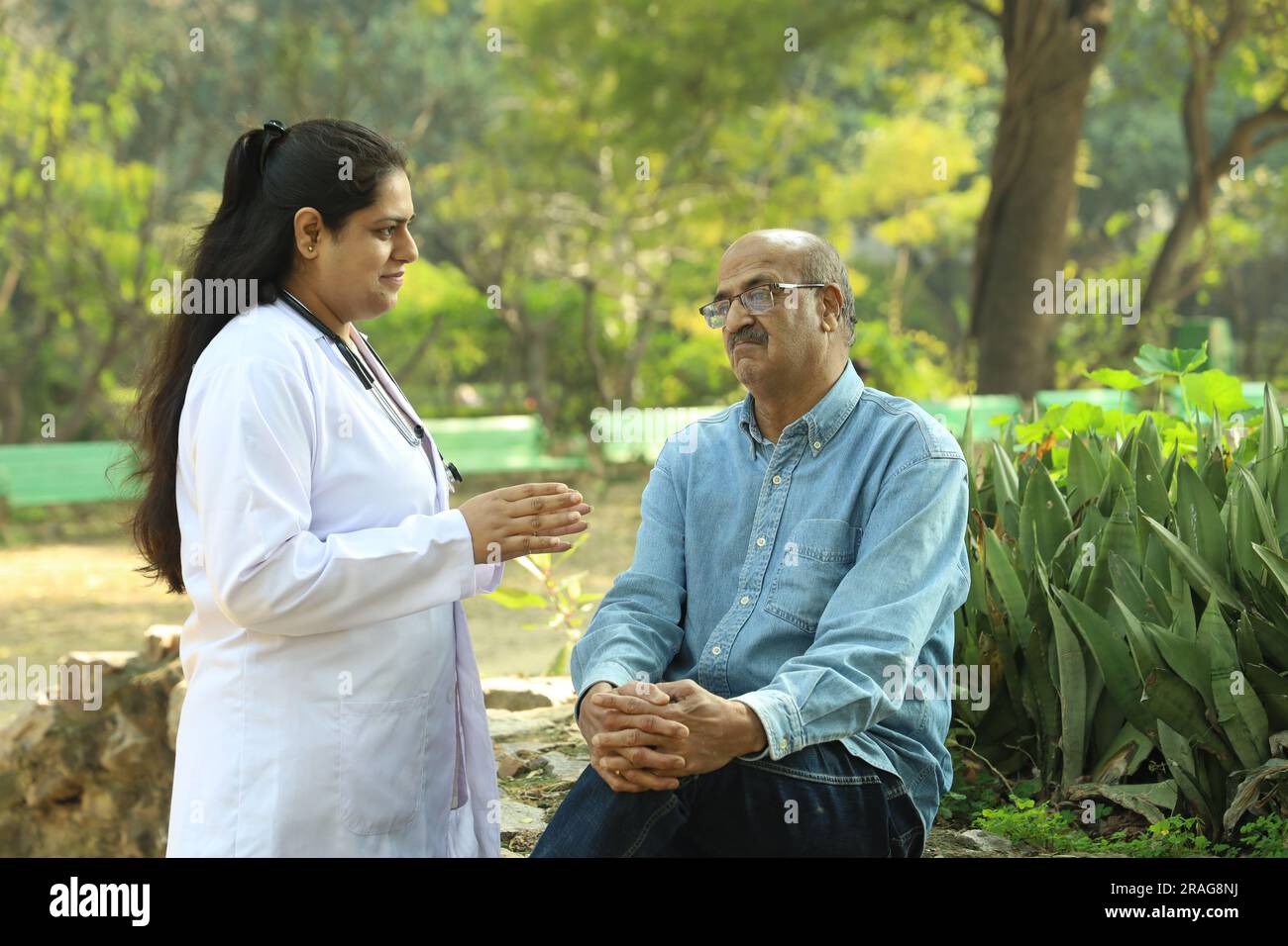 Femme médecin indienne examinant le patient âgé dans le parc de la ville dans l'après-midi. Banque D'Images