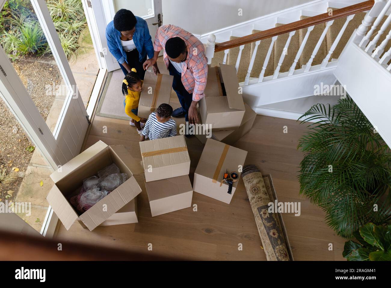 Vue à grand angle des parents afro-américains et des enfants portant des boîtes dans la nouvelle maison Banque D'Images