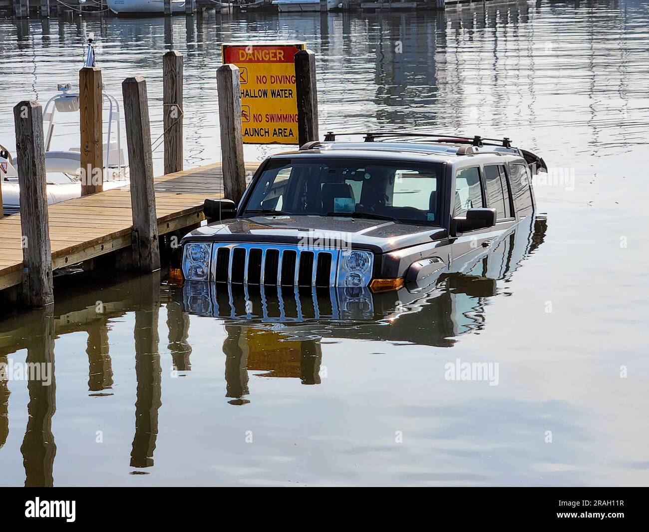 Véhicule SUV noir à moitié immergé dans l'eau d'un lac par un quai en bois Banque D'Images
