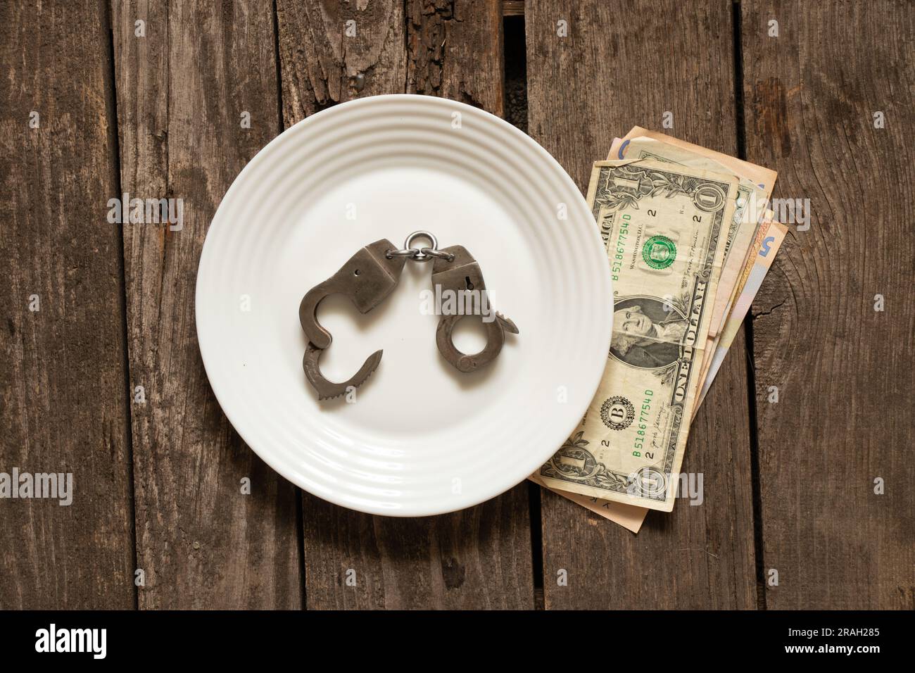 les dollars américains se trouvent sur une vieille table en bois à côté des menottes, des finances et de la corruption Banque D'Images