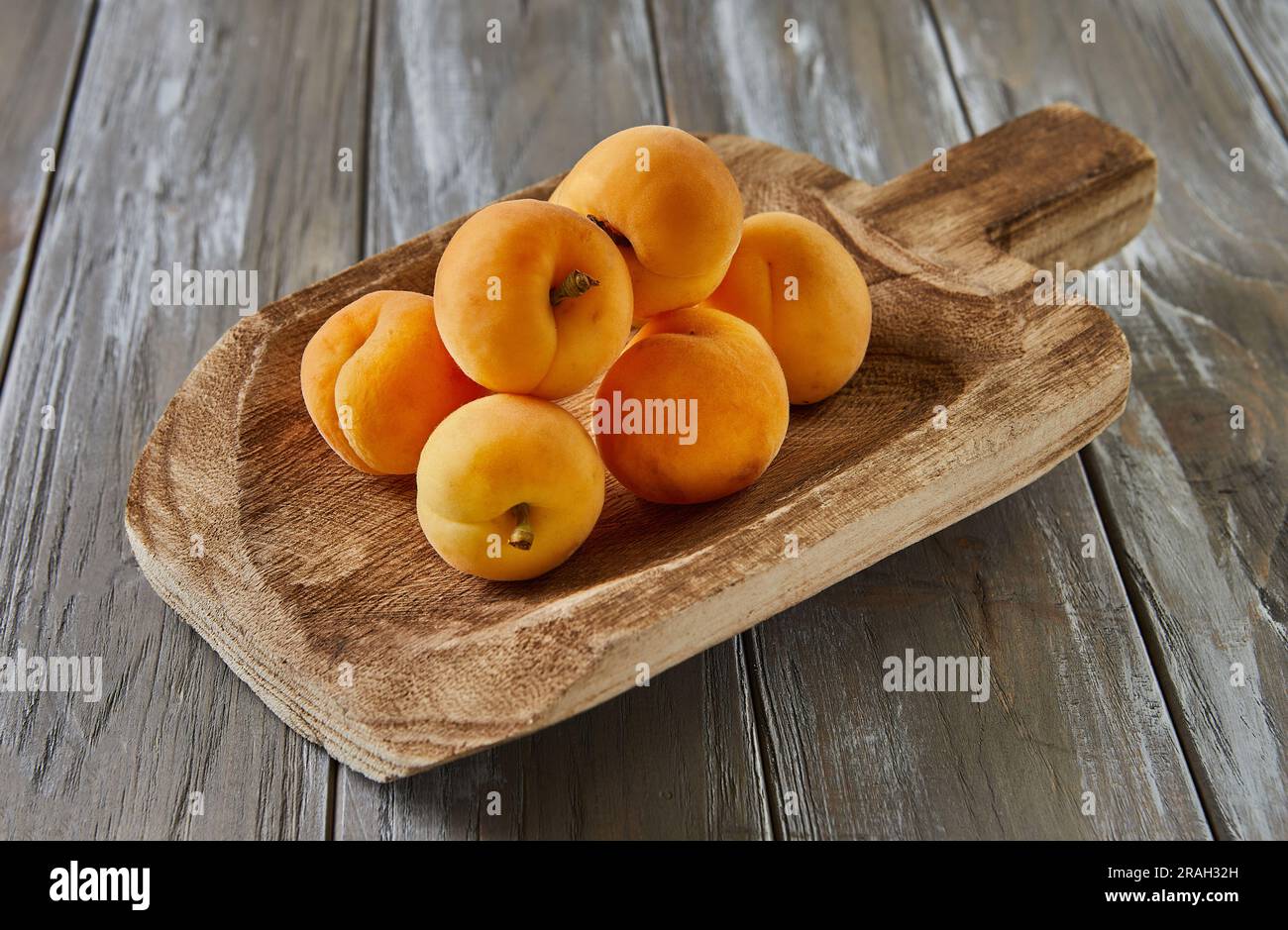 Abricots frais reposent sur la louche en bois sur fond en bois gris Banque D'Images