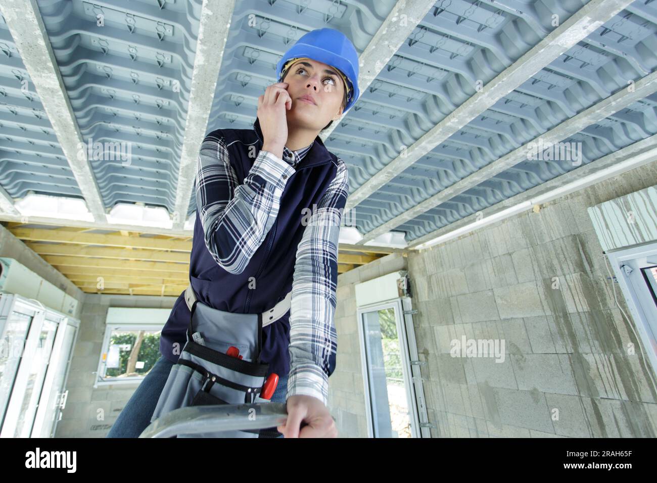 femme de construction sur escabeau inspectant le toit Banque D'Images