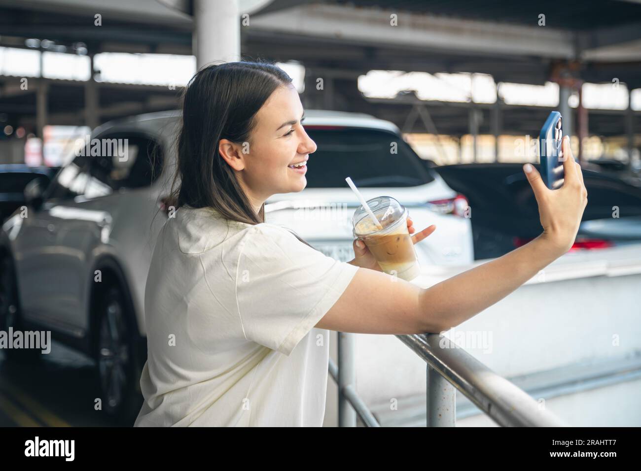 Une jeune femme avec une tasse de café dans le parking prend un selfie  Photo Stock - Alamy