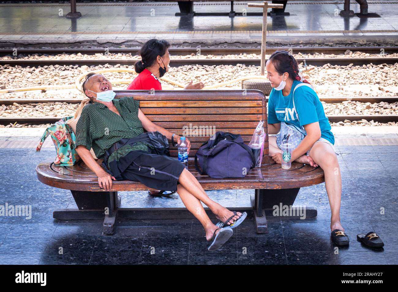 Les travailleurs thaïlandais rient en attendant un train de la gare de Hua Lamphong à Bangkok Banque D'Images