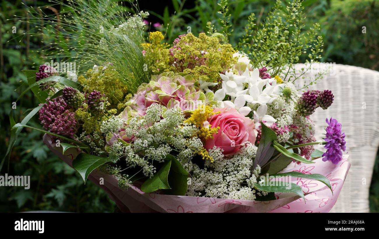 Un bouquet de belles fleurs d'été. Couleurs pastel. Une chaise en osier blanc dans le fond. Banque D'Images