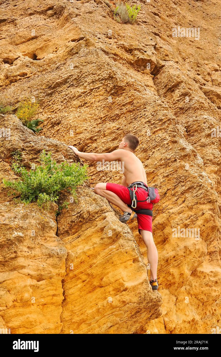 Jeune homme musclé grimpant sur le rocher Banque D'Images