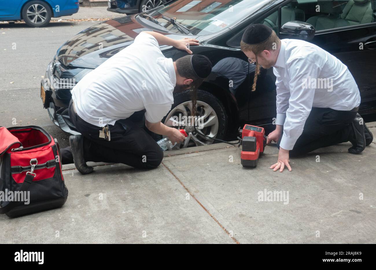 2 garçons juifs orthodoxes de Chavivim, une organisation de volontaires qui fournissent une assistance routière gratuite. Sur Ross St. À Williamsburg, Brooklyn, New York. Banque D'Images