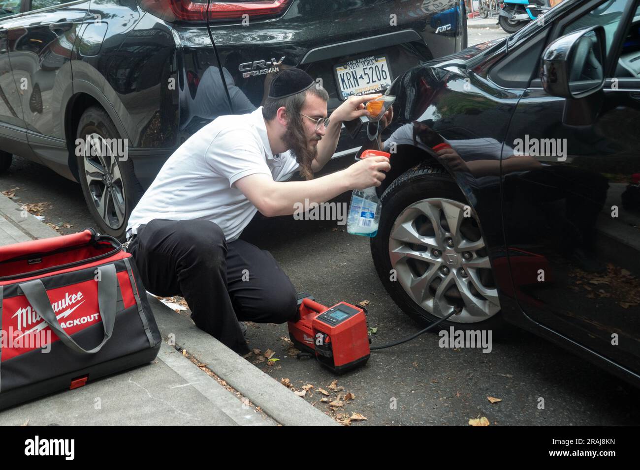 Un volontaire de Chavivim vérifie l'étanchéité d'un pneu sur la rue Ross à Williamsburg. Il est bénévole et fournit une assistance routière. Chavivim signifie les êtres chers. Banque D'Images