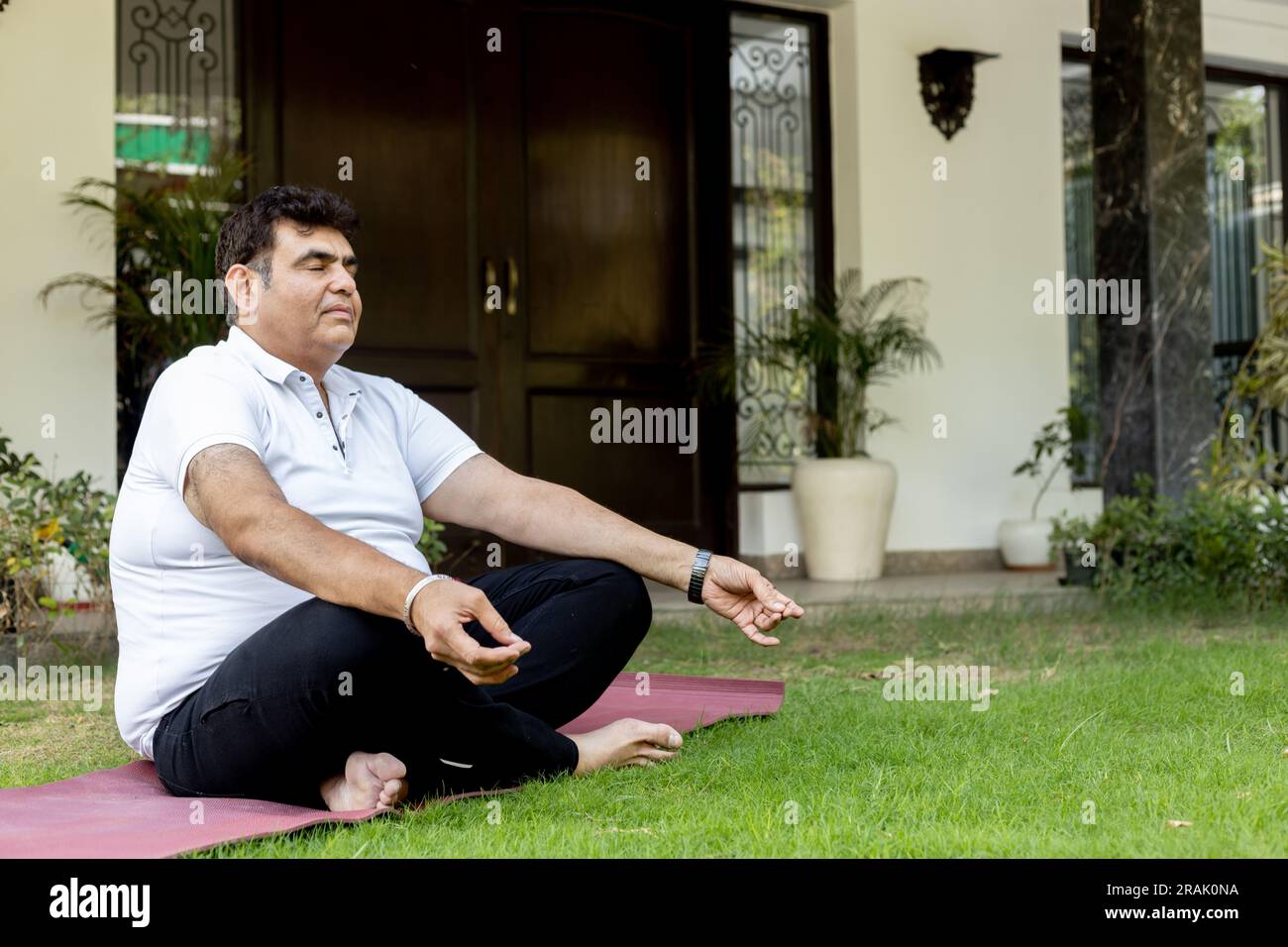 Indian Fat Male faisant du yoga dans le jardin de la maison Banque D'Images