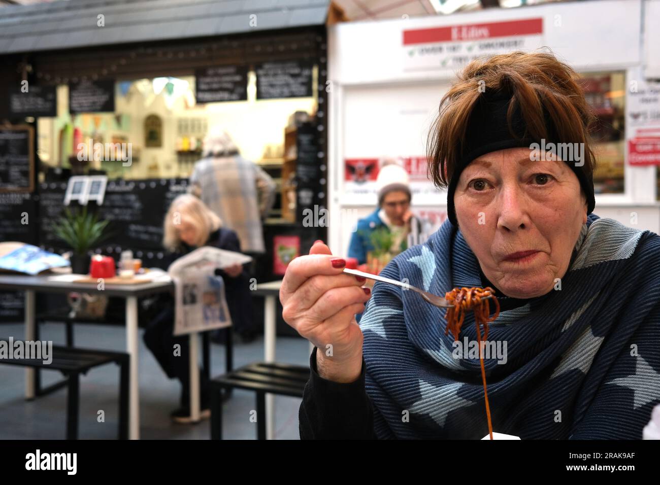 Femme mangeant des nouilles dans un café du marché en Angleterre, en Grande-Bretagne, au Royaume-Uni Banque D'Images