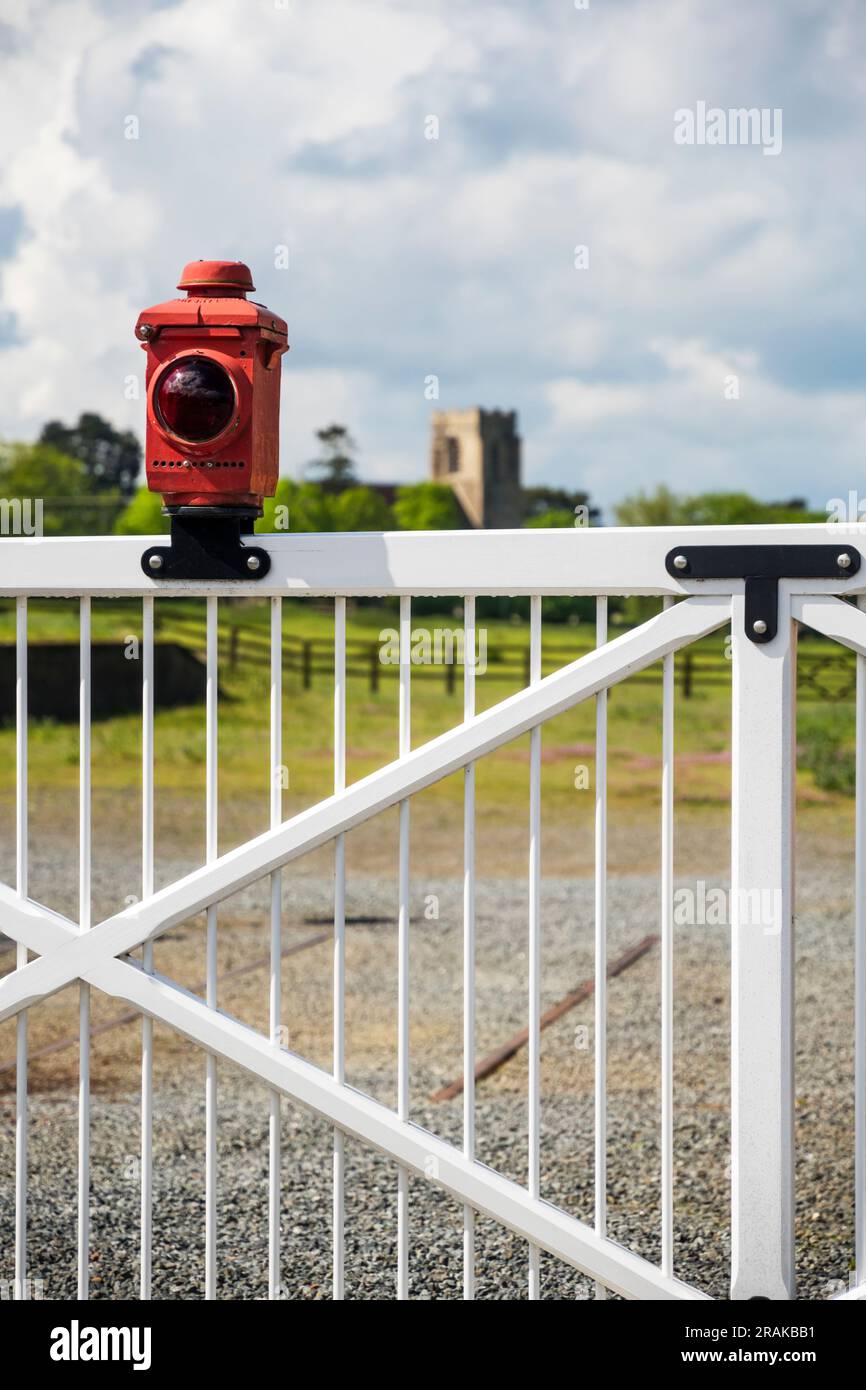 Feu d'arrêt rouge sur un ancien ensemble de portes de passage à niveau dans un village anglais. Banque D'Images