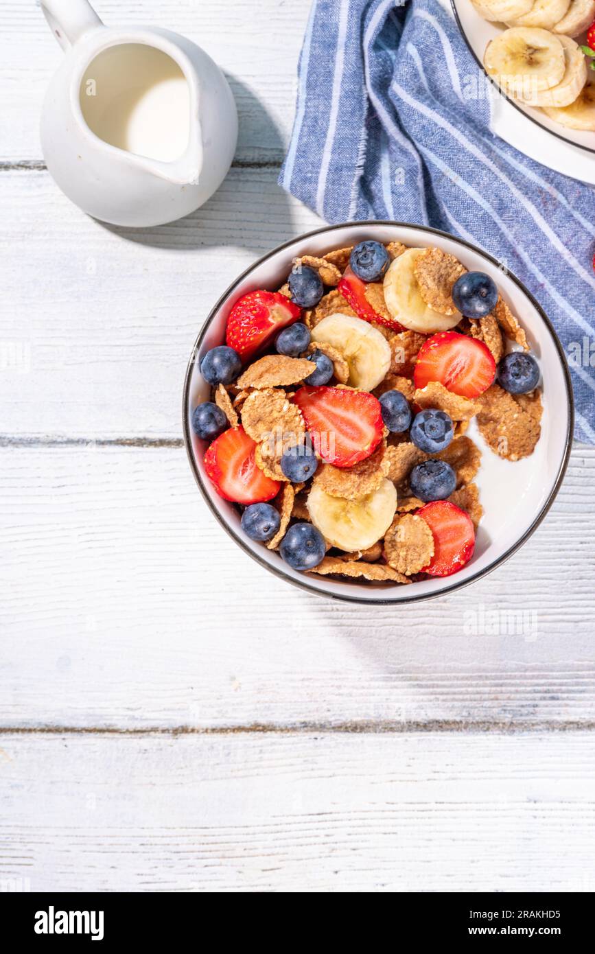 Petit déjeuner d'été diététique vitaminique sain. Céréales flocons multigrains avec yaourt ou lait et fraises, myrtilles, sur l'espace de copie de table de cuisine Banque D'Images