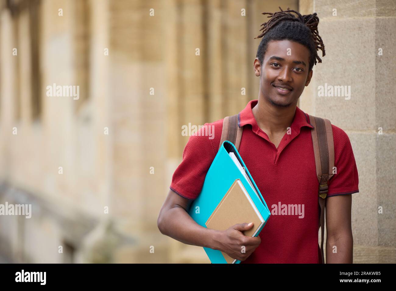 Portrait d'un étudiant portant des dossiers à l'extérieur du bâtiment de l'université d'Oxford, au Royaume-Uni Banque D'Images